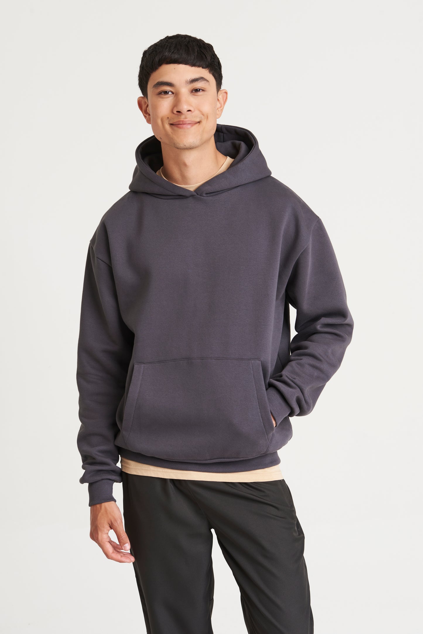 Person wearing a gray hoodie and black pants on a white background